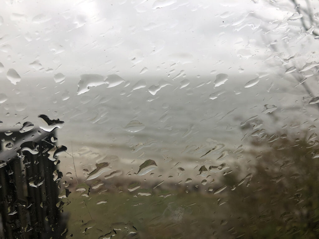 A rain-splattered window on a very cloudy day.