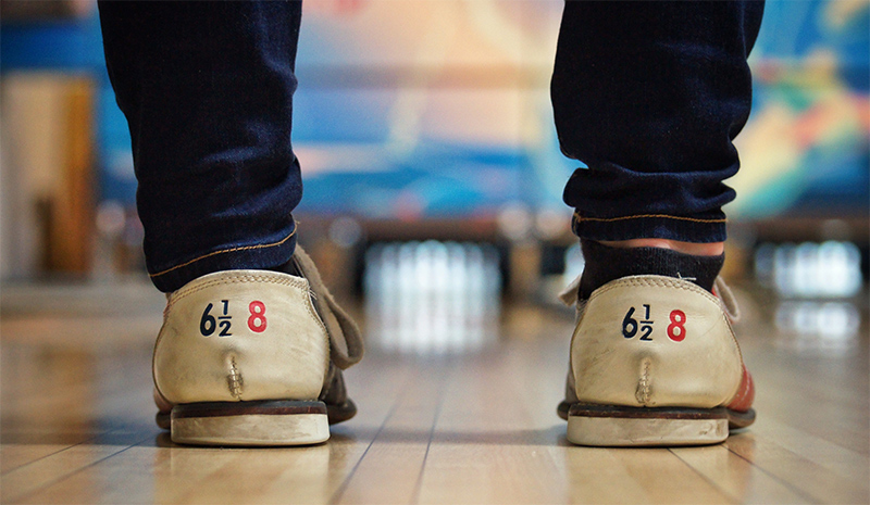 View of 10 bowling pins between the legs of a bowler