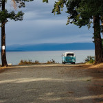 A VW bus at the end of a road leading to a lake