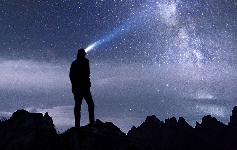 Person shining headlamp toward the night sky