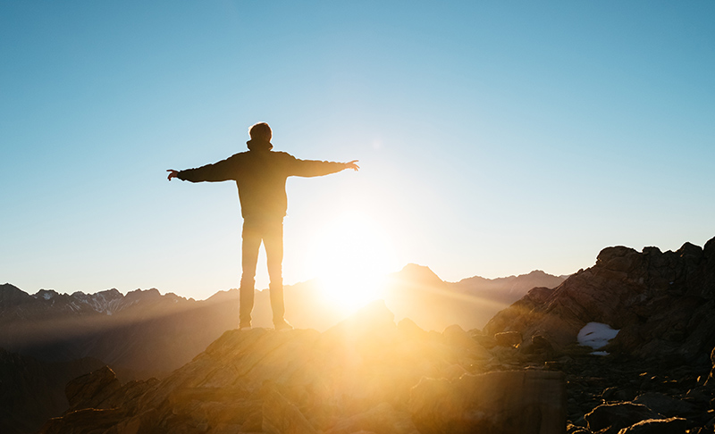 Person standing in the light of a sunrise.