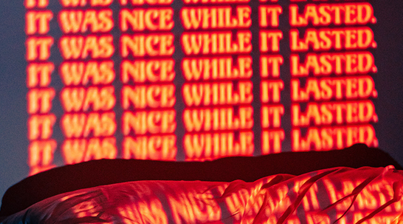 It Was Nice While It Lasted projected (in orange text) against a dark wall.