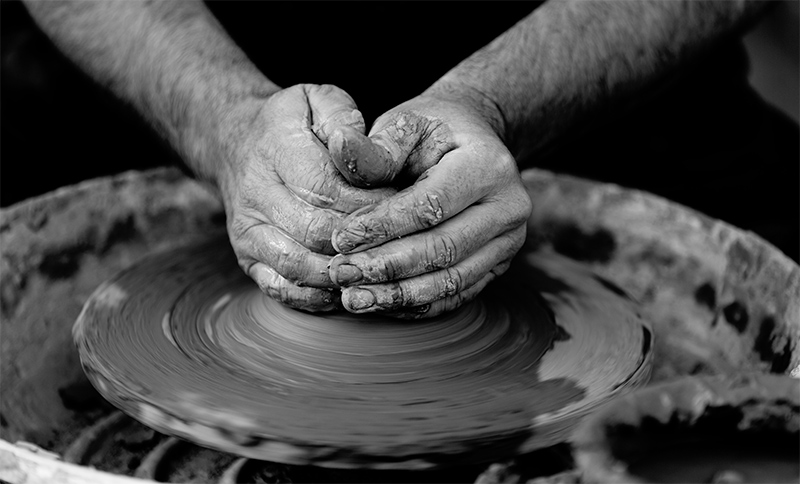 Hands shaping a bowl on a potter's wheel