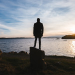 Person standing on a rock at sunset