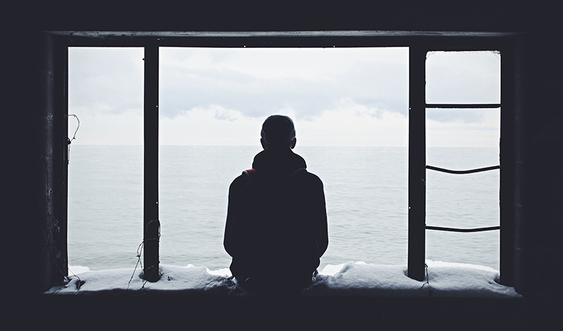 Person silhoutted while sitting in a window.