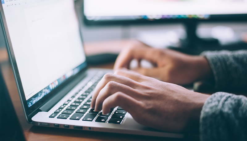 Hands typing on a laptop keyboard.